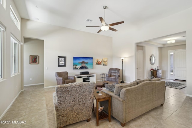 living room featuring light tile patterned floors, visible vents, baseboards, and ceiling fan
