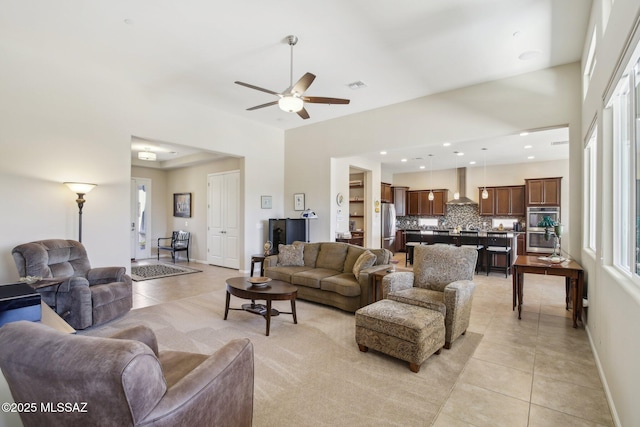 living room with light tile patterned floors, visible vents, baseboards, and a ceiling fan