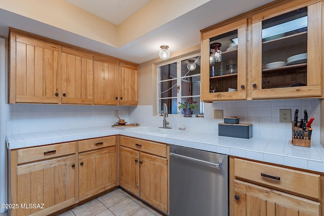 kitchen featuring tasteful backsplash, a sink, light tile patterned flooring, and stainless steel dishwasher