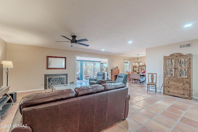 living room with light tile patterned floors, visible vents, a fireplace, and ceiling fan with notable chandelier
