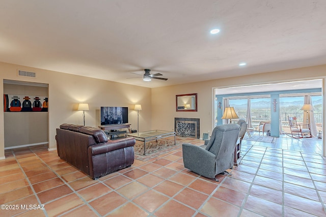 living area with light tile patterned flooring, a fireplace, visible vents, and ceiling fan