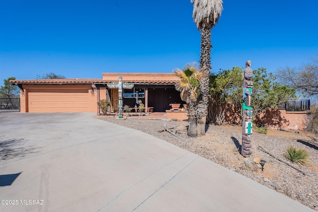 view of front of property featuring fence, driveway, an attached garage, stucco siding, and a tiled roof