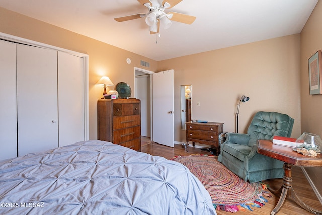 bedroom featuring visible vents, wood finished floors, a closet, baseboards, and ceiling fan