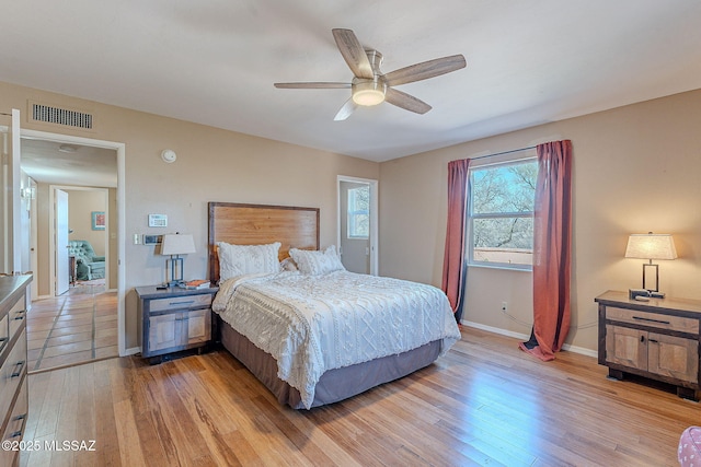 bedroom with light wood finished floors, visible vents, a ceiling fan, and baseboards