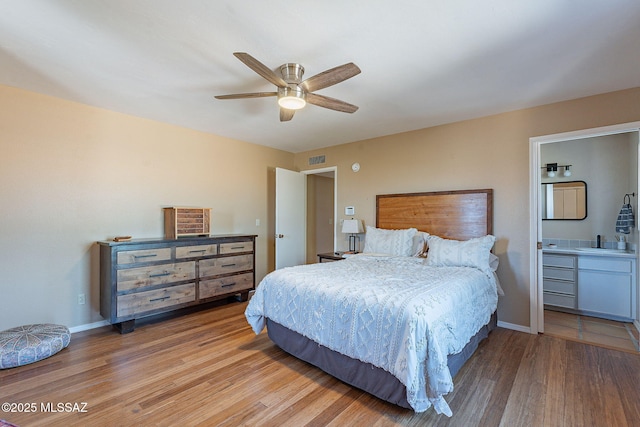 bedroom with a sink, visible vents, baseboards, and wood finished floors