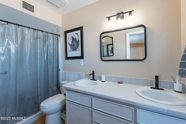 bathroom with a sink, visible vents, toilet, and double vanity