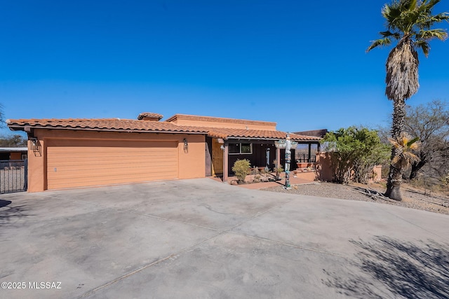 view of front of house featuring fence, a tiled roof, concrete driveway, stucco siding, and a garage