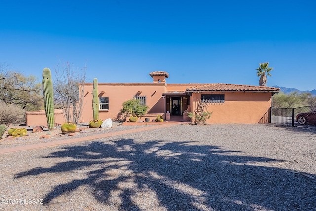 view of front of home with a tile roof, fence, and stucco siding