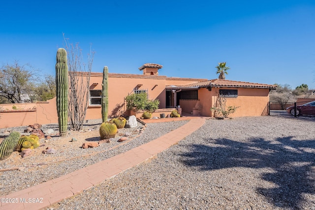 view of front of home with a tiled roof, stucco siding, and fence