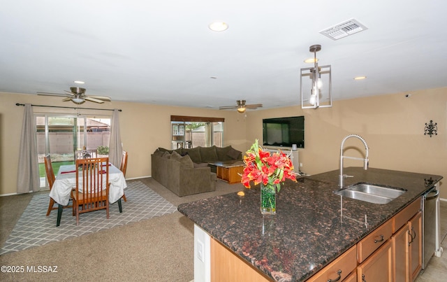 kitchen with visible vents, a sink, a ceiling fan, and light carpet
