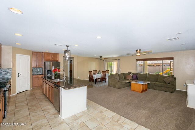 kitchen with a sink, a ceiling fan, open floor plan, stainless steel appliances, and visible vents