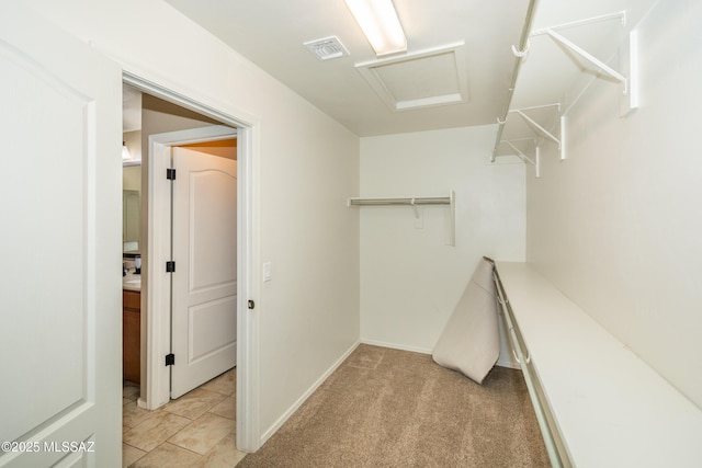 walk in closet featuring light carpet, attic access, and visible vents