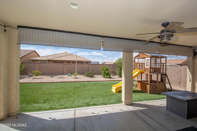 exterior space featuring a fenced backyard, a playground, and a ceiling fan