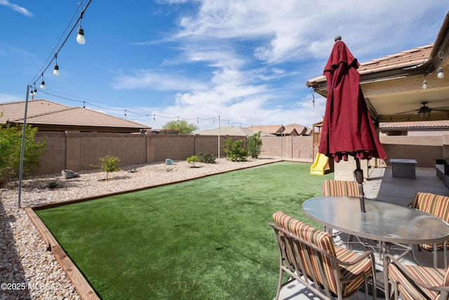 view of yard featuring a fenced backyard, a patio, outdoor dining space, ceiling fan, and a playground