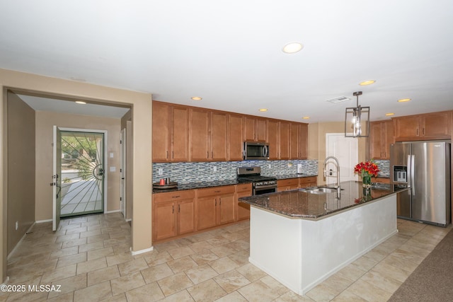 kitchen with a sink, dark stone countertops, stainless steel appliances, visible vents, and decorative backsplash