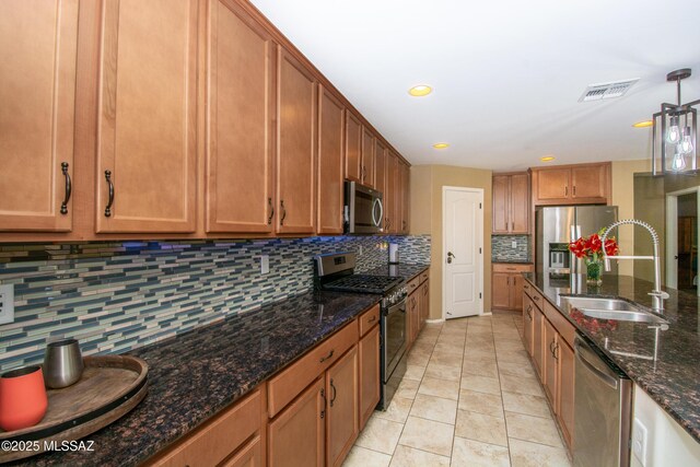 kitchen with a sink, brown cabinetry, stainless steel appliances, light tile patterned floors, and visible vents