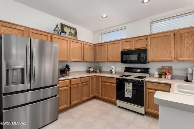 kitchen with light countertops, gas range oven, stainless steel refrigerator with ice dispenser, and black microwave