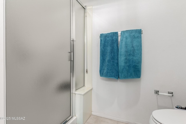 bathroom featuring toilet, a stall shower, tile patterned flooring, and baseboards