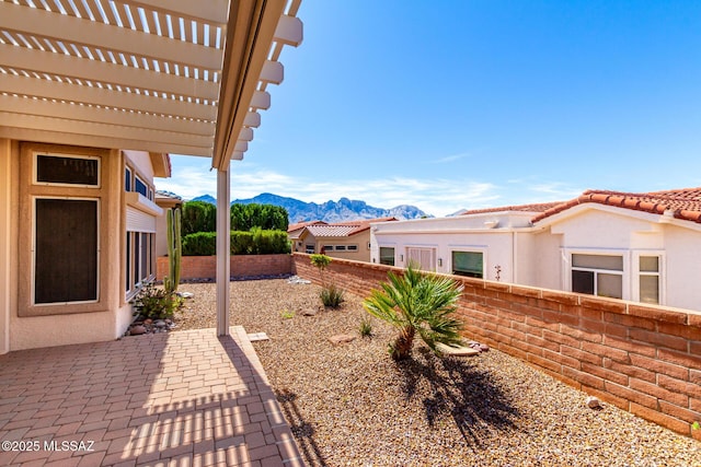 view of yard featuring a mountain view, a fenced backyard, a pergola, and a patio area