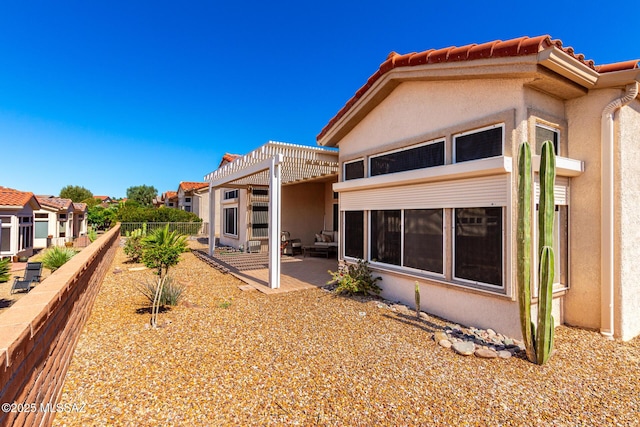rear view of house with fence, a tiled roof, a patio, stucco siding, and a pergola