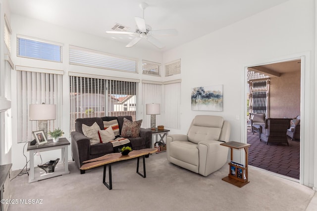 living room with carpet flooring, a ceiling fan, a towering ceiling, and visible vents