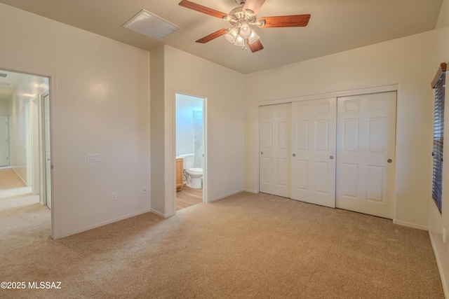 unfurnished bedroom with a closet, visible vents, light carpet, baseboards, and ensuite bathroom