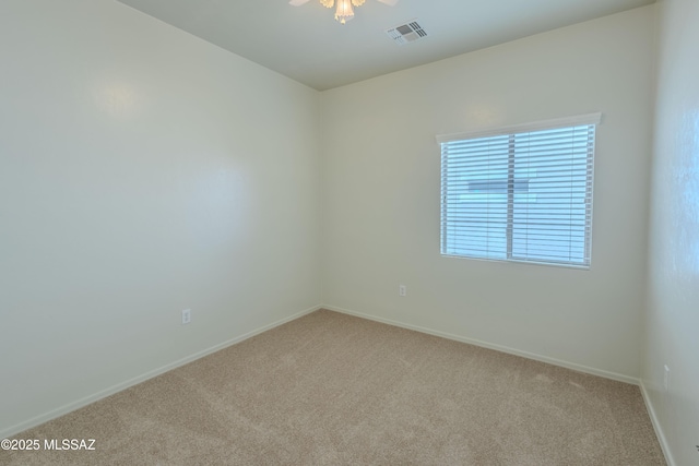 carpeted spare room featuring a ceiling fan, visible vents, and baseboards