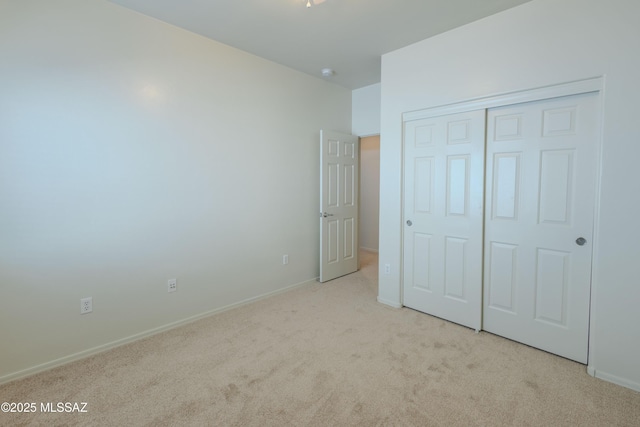 unfurnished bedroom with a closet, carpet flooring, and baseboards