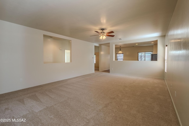 carpeted spare room featuring a ceiling fan and baseboards