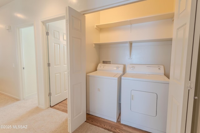 clothes washing area featuring washing machine and dryer, light colored carpet, and laundry area