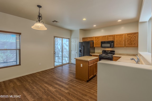kitchen with visible vents, light countertops, a kitchen island, black appliances, and brown cabinetry