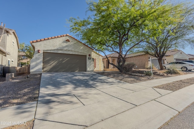 mediterranean / spanish-style home featuring stucco siding, driveway, a tiled roof, and an attached garage