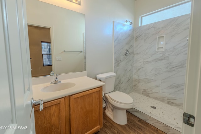 full bath featuring toilet, a tile shower, wood finished floors, and vanity