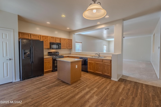 kitchen featuring a sink, light countertops, a center island, black appliances, and dark wood-style flooring