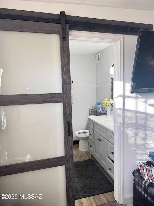 bathroom featuring visible vents, toilet, vanity, and wood finished floors