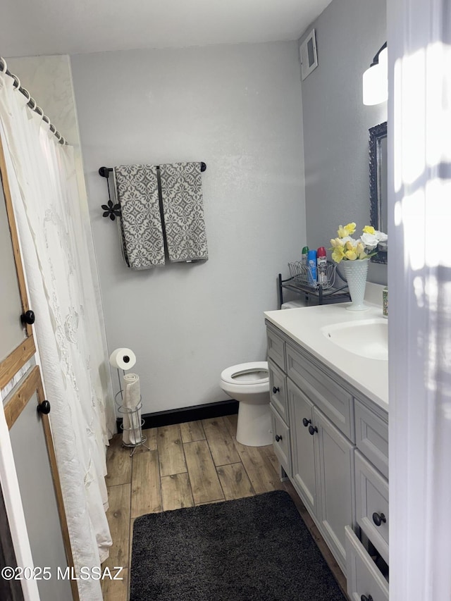 bathroom featuring vanity, toilet, visible vents, curtained shower, and wood finished floors