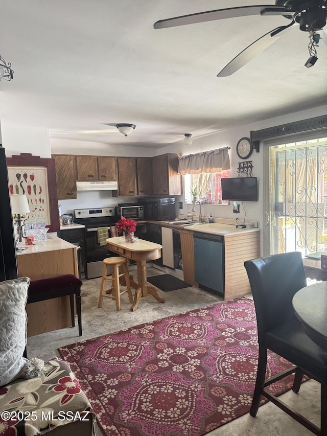 kitchen with light countertops, a sink, a ceiling fan, appliances with stainless steel finishes, and under cabinet range hood