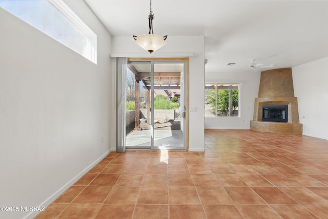 entrance foyer with light tile patterned floors, baseboards, a large fireplace, and a ceiling fan