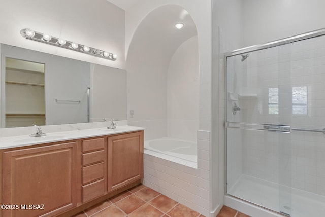 full bathroom featuring tile patterned floors, a bath, a stall shower, and a sink