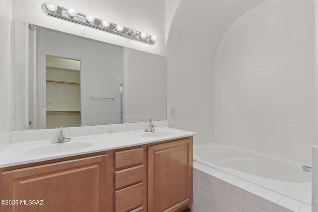 full bathroom with double vanity, a garden tub, and a sink