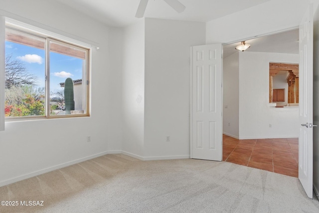 spare room featuring tile patterned floors, baseboards, carpet floors, and ceiling fan