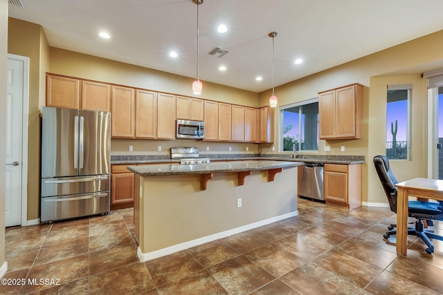 kitchen featuring stone countertops, a breakfast bar, a center island, stainless steel appliances, and visible vents