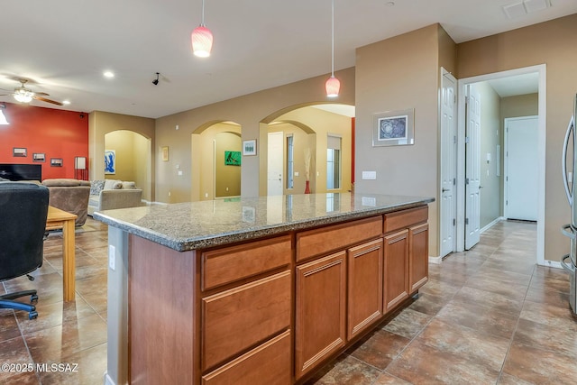 kitchen with stone countertops, visible vents, arched walkways, and a ceiling fan