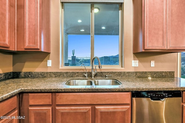 kitchen with dark stone countertops, a sink, brown cabinets, and dishwasher