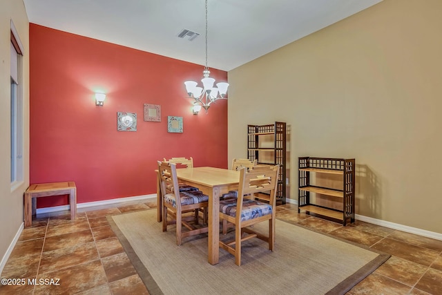 dining room featuring baseboards, stone finish floor, visible vents, and a chandelier