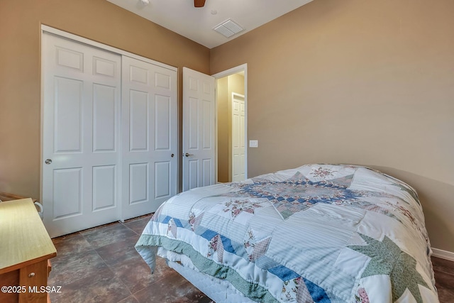 bedroom with a closet, visible vents, stone finish flooring, baseboards, and a ceiling fan