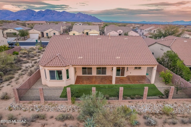 exterior space with a tile roof, a fenced front yard, stucco siding, a mountain view, and a yard