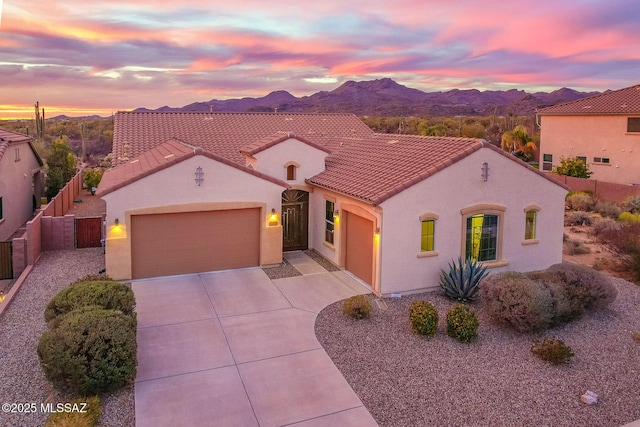 mediterranean / spanish-style house featuring a tiled roof, a garage, concrete driveway, stucco siding, and a mountain view