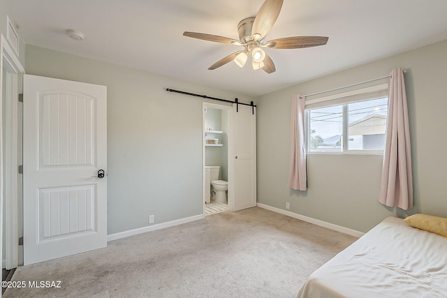 carpeted bedroom featuring a barn door, ceiling fan, ensuite bath, visible vents, and baseboards