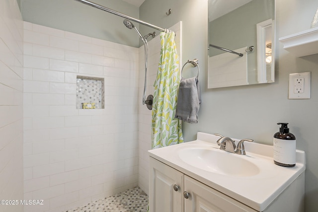 bathroom with tiled shower and vanity